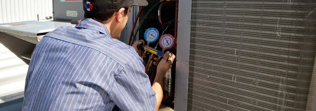 HVAC technician servicing a condenser unit in Collegedale